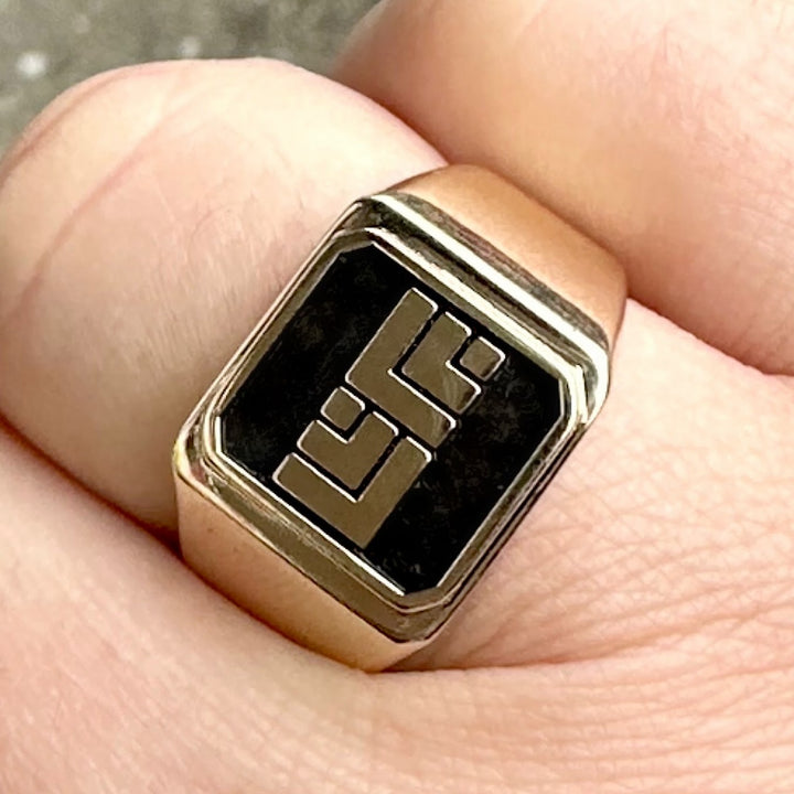 Man finger wearing yellow gold with black design ring