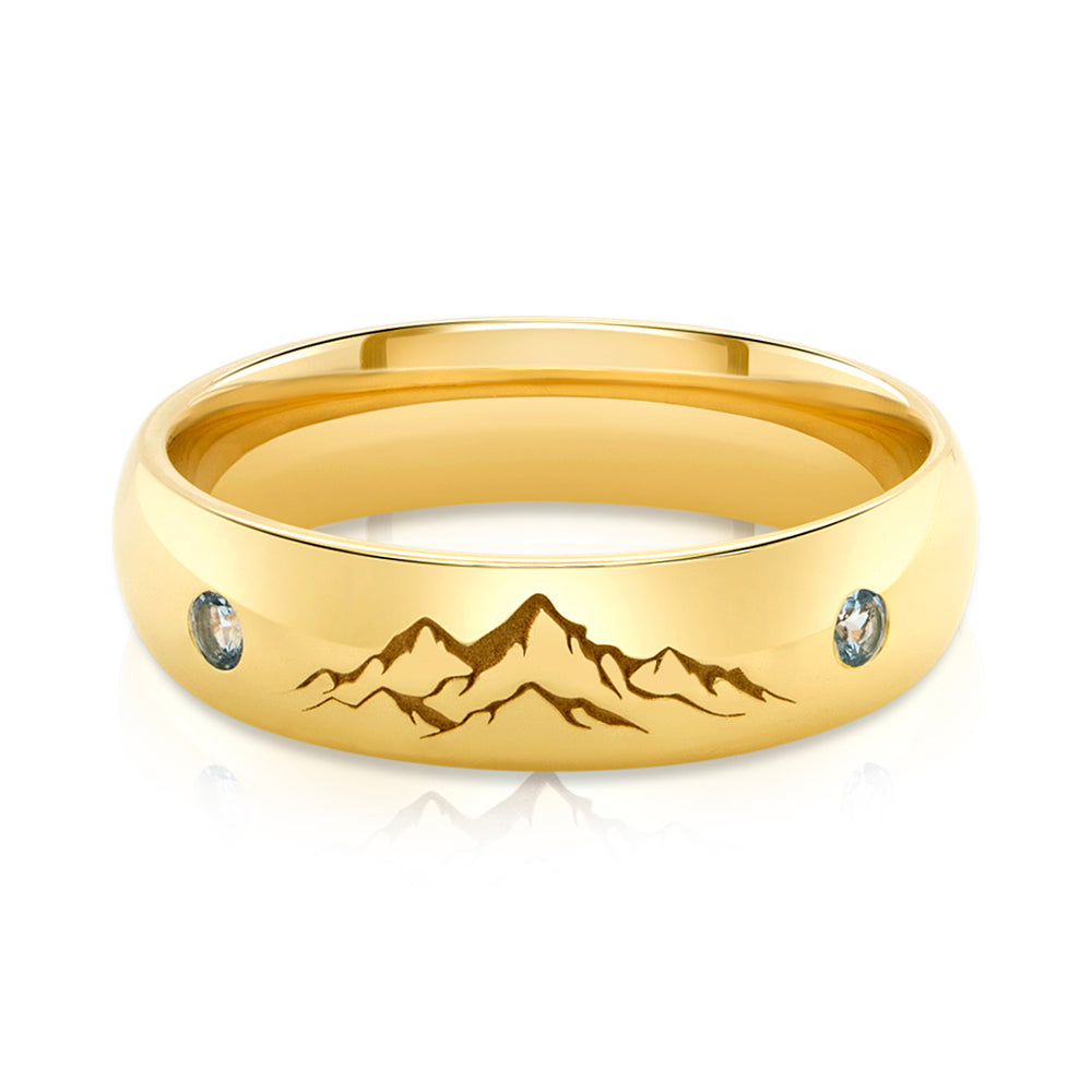 A front view of the Custom Engraved Wedding band, complete with mountain artwork engraving and the natural aquamarine stone on each side