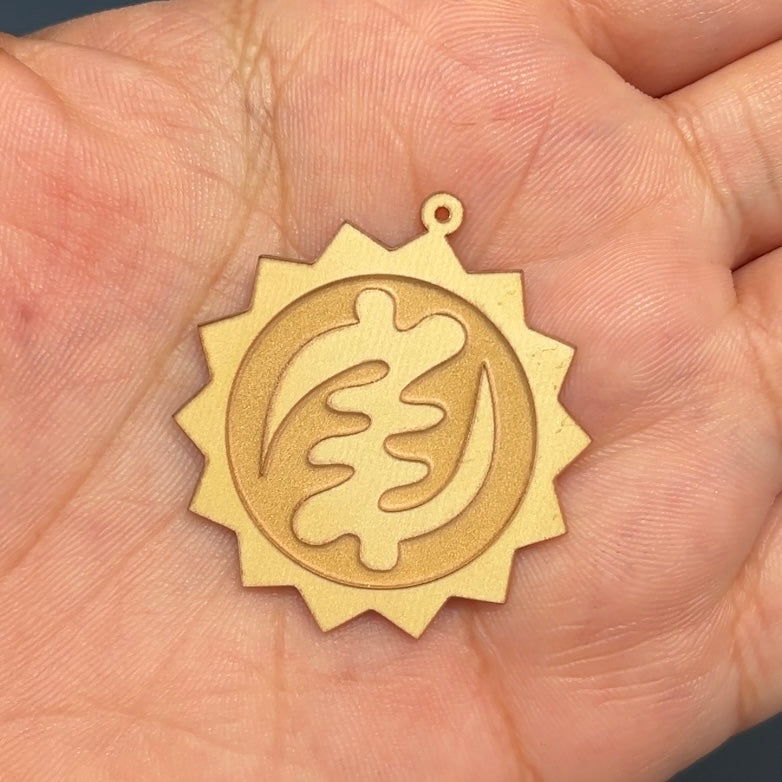 The raw piece of the 14 Karat Custom Sun Pendant with the "Nyame Ye Ohene" symbol in the center after it was cut out from a sheet of 14 Karat Yellow Gold with the Laser Cutting and Engraving Machine